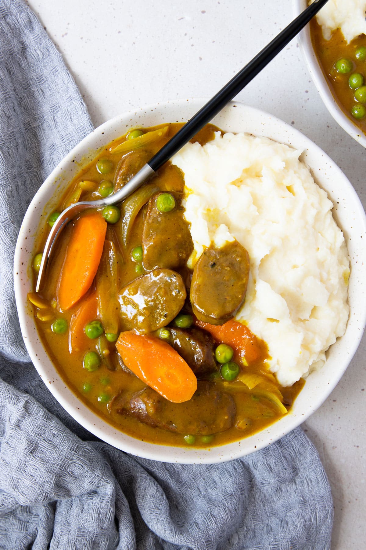 a bowl of curried sausages and mashed potatoes on a table.