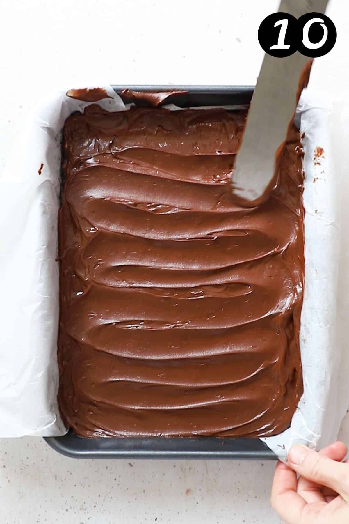 slice mixture topped with chocolate ganache in a tin.