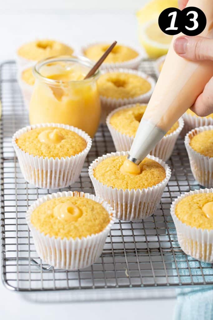 a piping bag piping lemon curd into the centre of a cupcake.