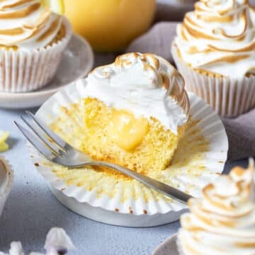 half a cupcake on a paper case. It is filled with lemon curd and topped with toasted meringue.