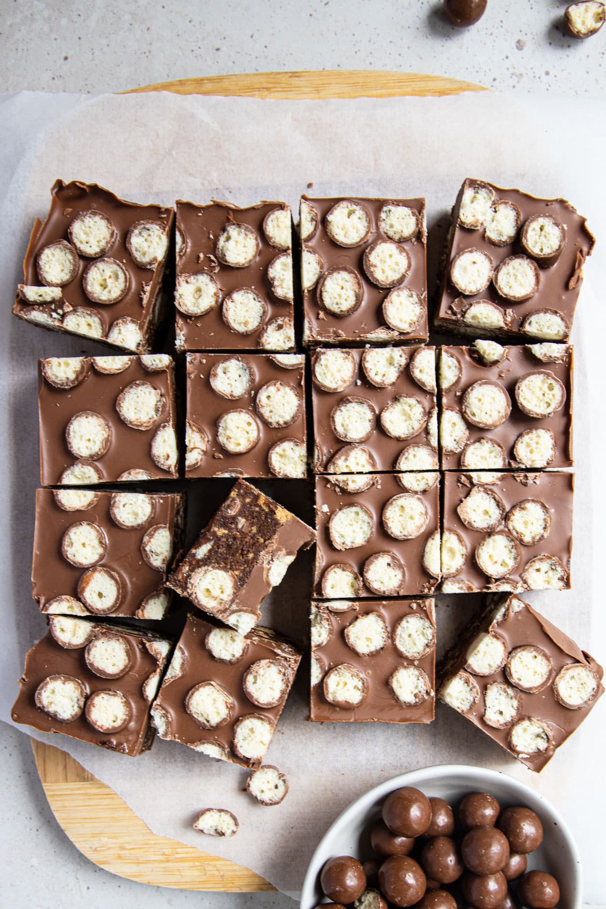 a slice topped with chocolate cut into pieces on a wooden board.