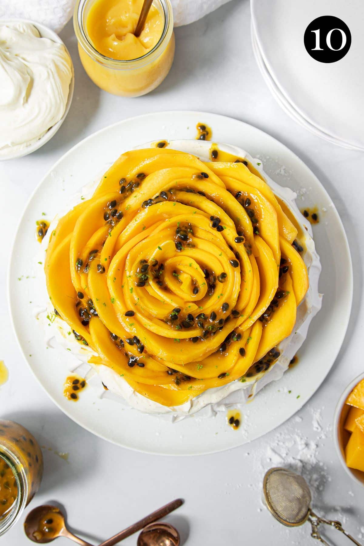 finished pavlova on a plate topped with mango and passion fruit.