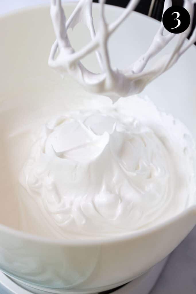 fluffy meringue showing stiff peaks in a mixer bowl.