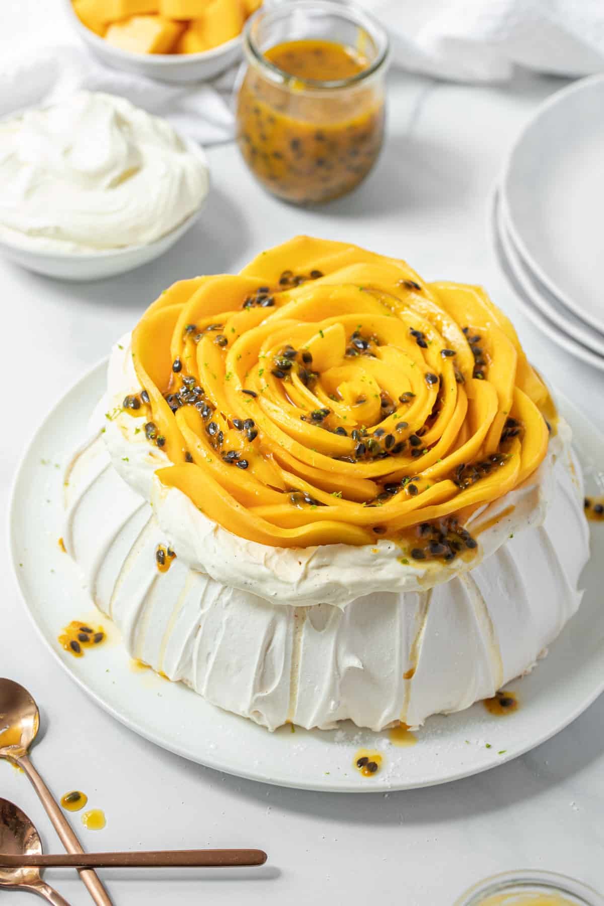 pavlova on a plate, topped with slices of mango and passion fruit.