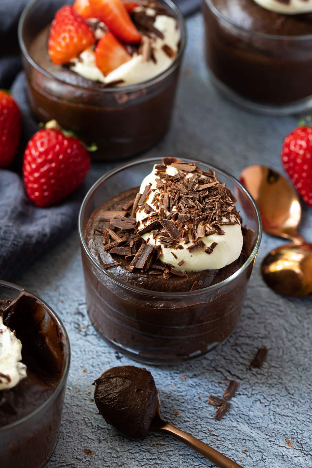 chocolate mousse in glass jars, topped with cream and strawberries.