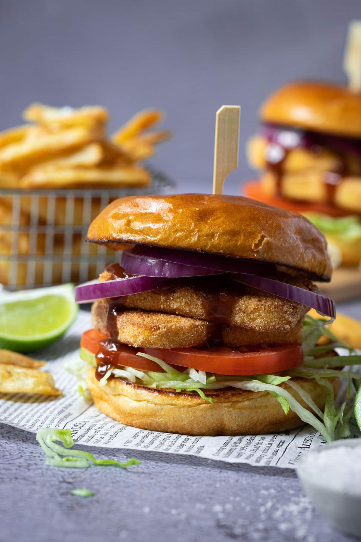 a finished burger on a table, surrounded by chips and salad.