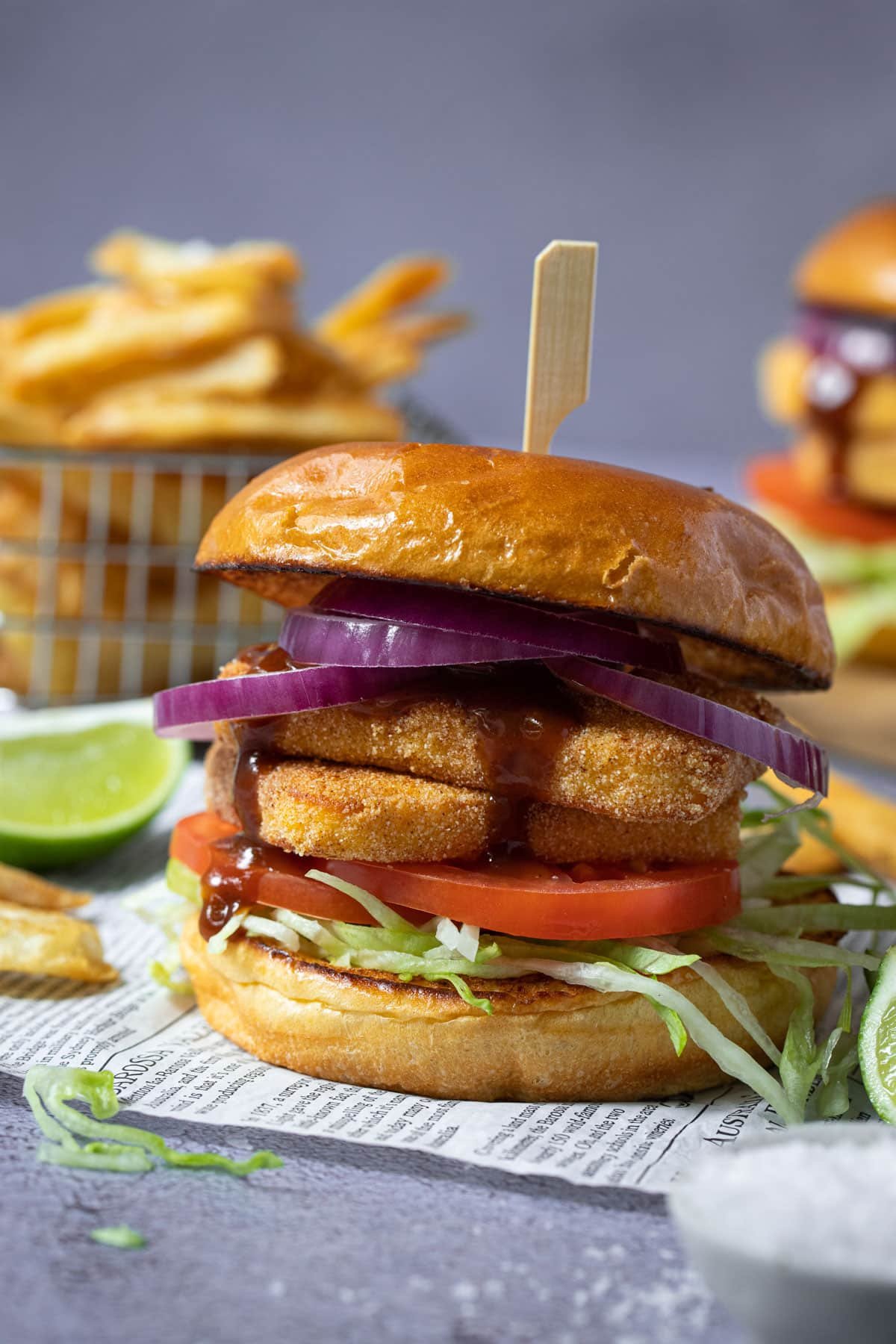 a burger filled with halloumi pieces, salad and sauce on a table.