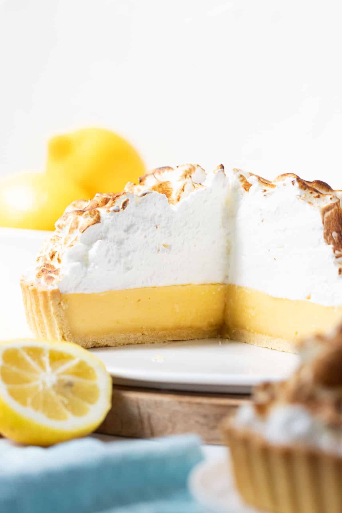lemon meringue pie cut in half on a white plate.