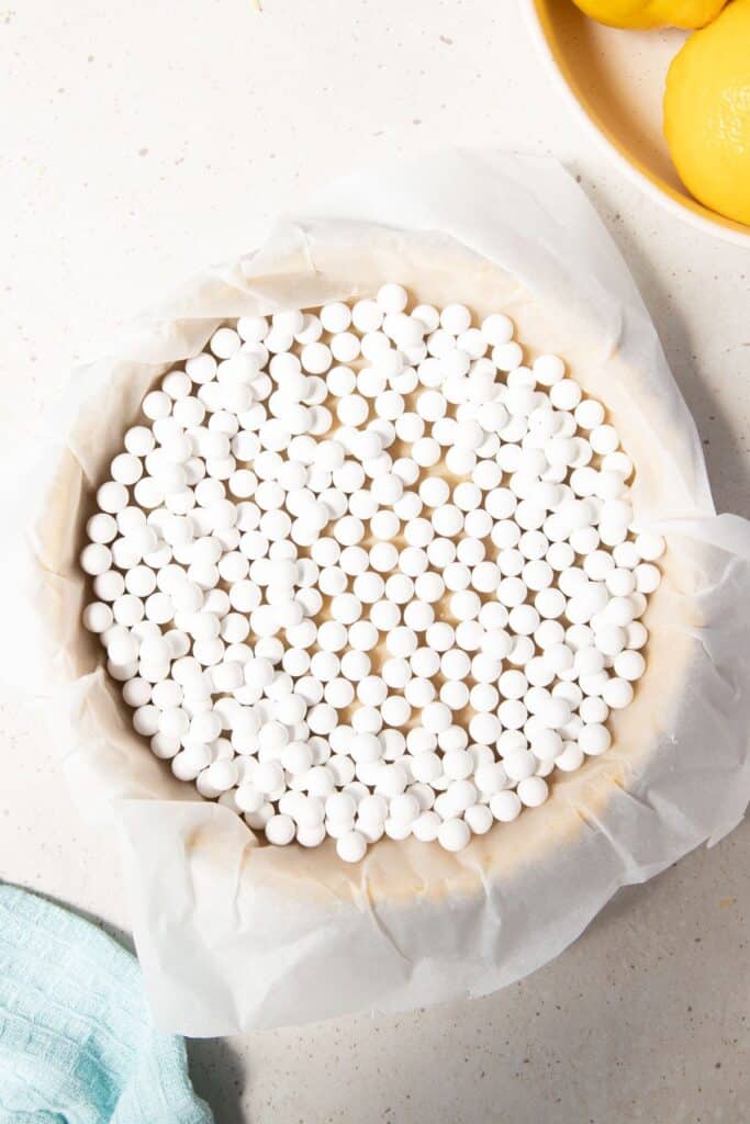 pastry in a pie tin covered with paper and baking beads.