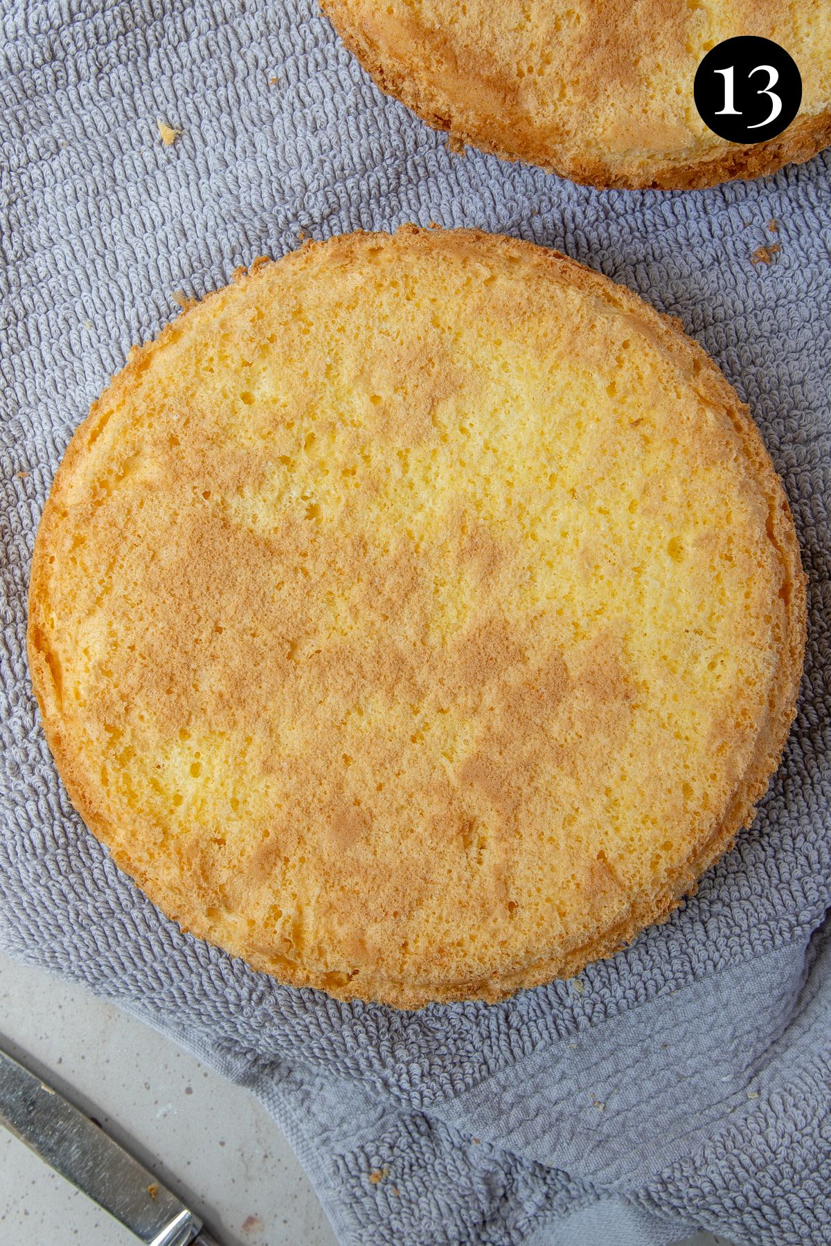 sponge cake on a towel over a wire rack.