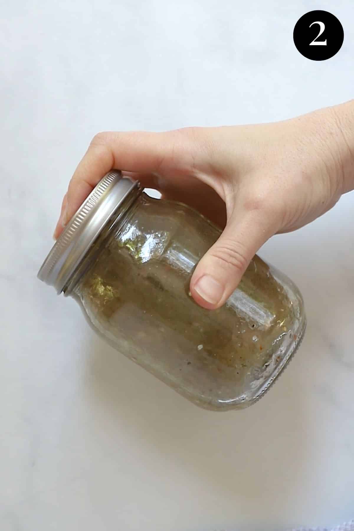 salad dressing being shaken in a mason jar.