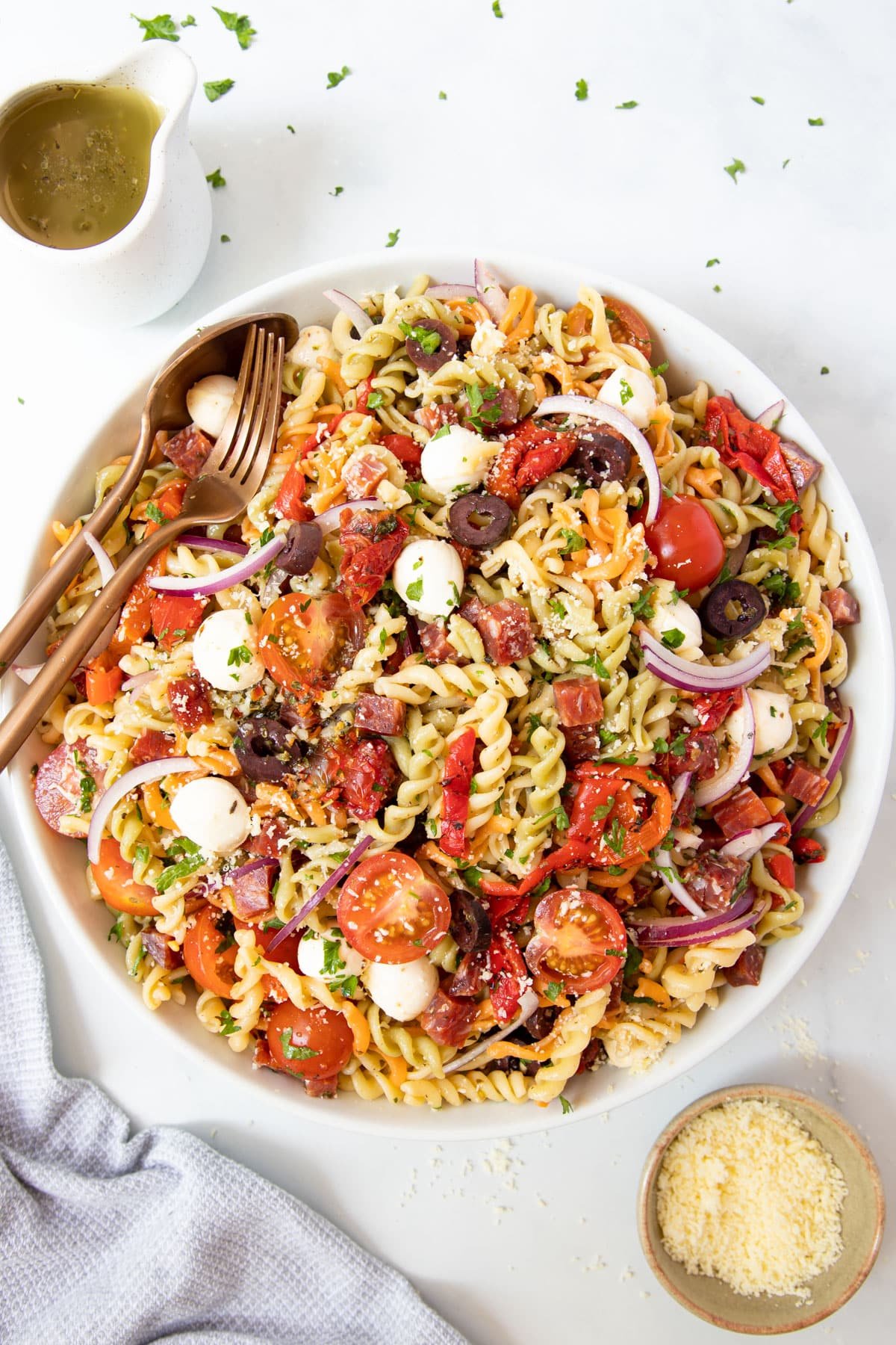 finished pasta salad in a bowl topped with salami and cherry tomatoes.