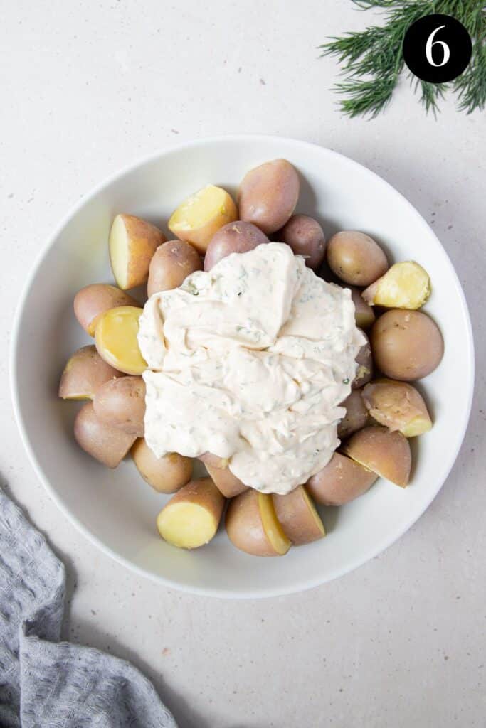 potatoes in a bowl topped with a mayonnaise dressing.