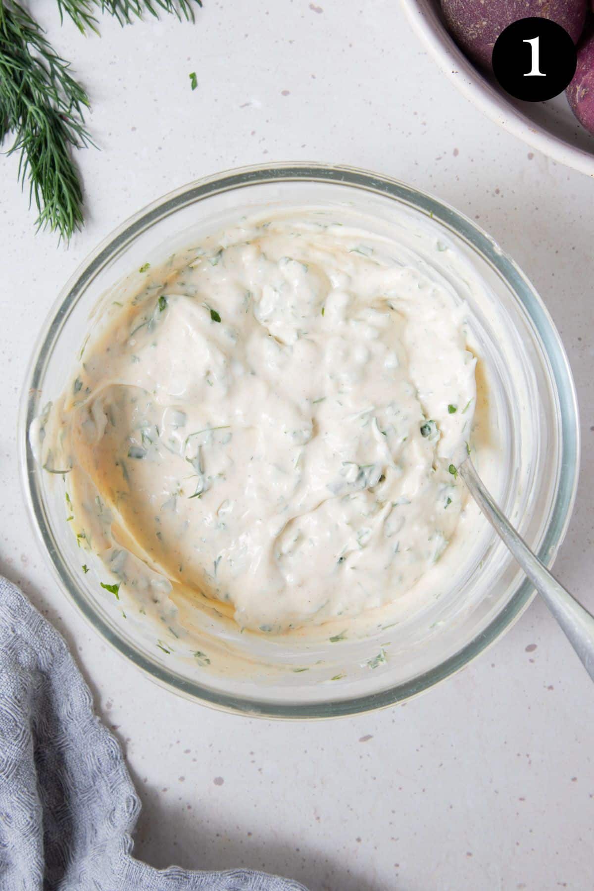 potato salad dressing in a glass bowl with a spoon.