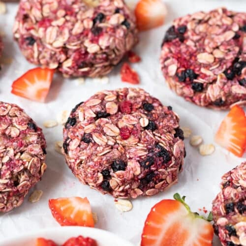 raspberry oatmeal cookies on a table with sliced strawberries.