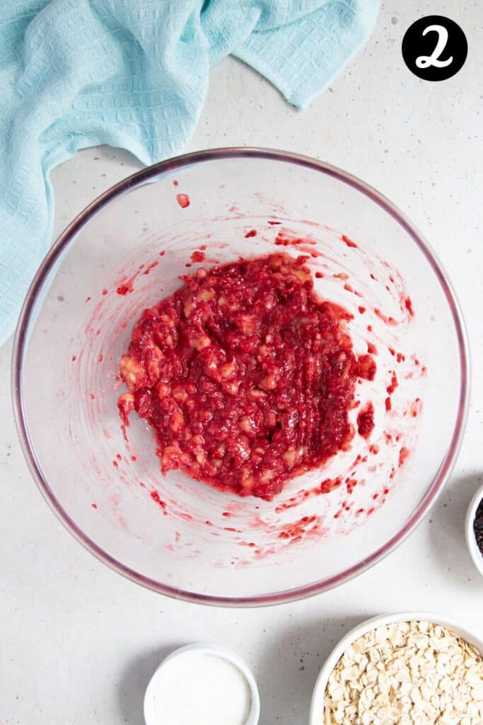 mashed raspberries and banana in a mixing bowl.