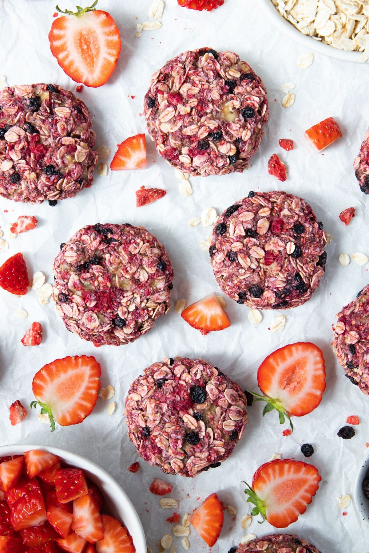 oat cookies on a table with pieces of raspberry and strawberries.