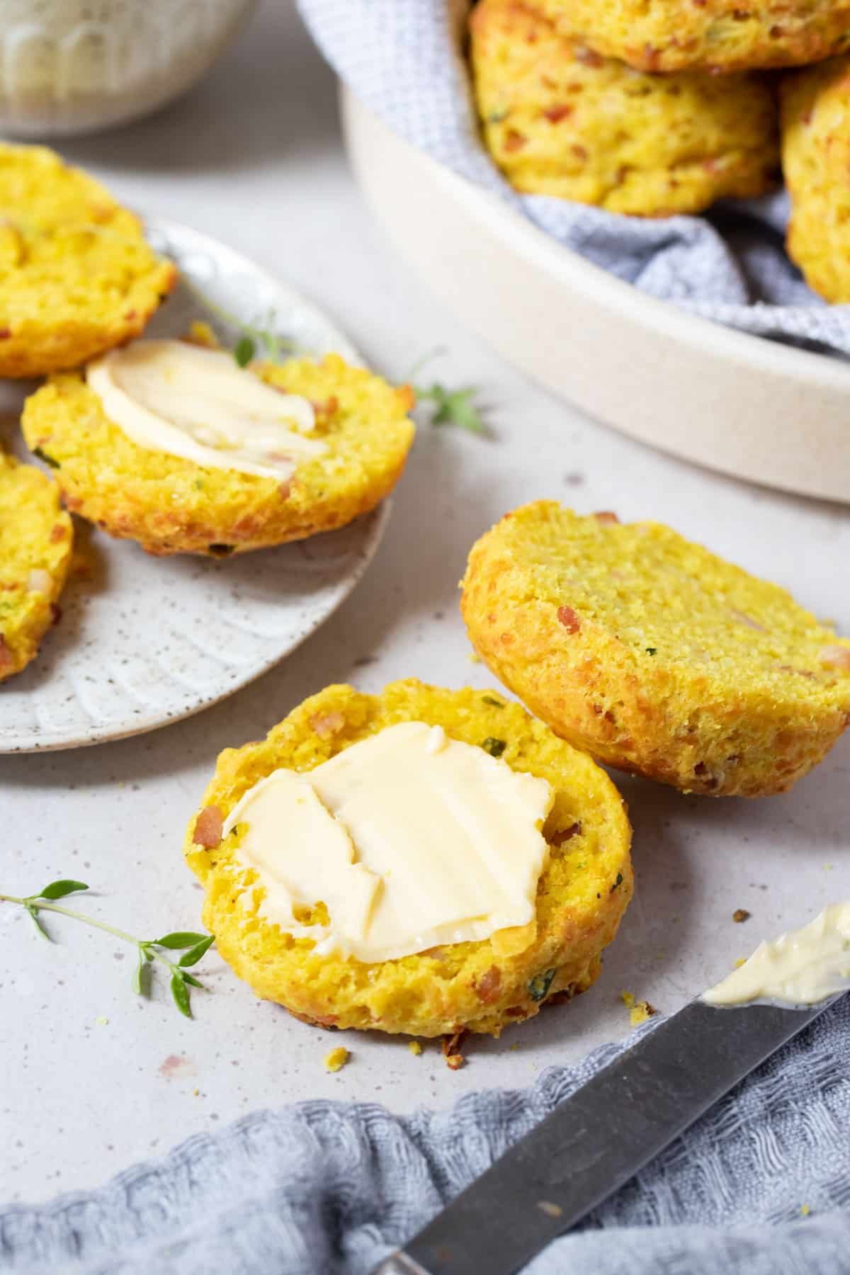 a scone cut in half on a table and covered with butter.