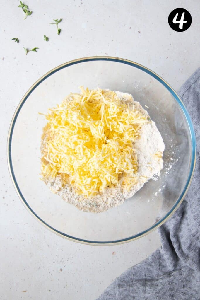 grated butter added to flour mixture in a bowl.