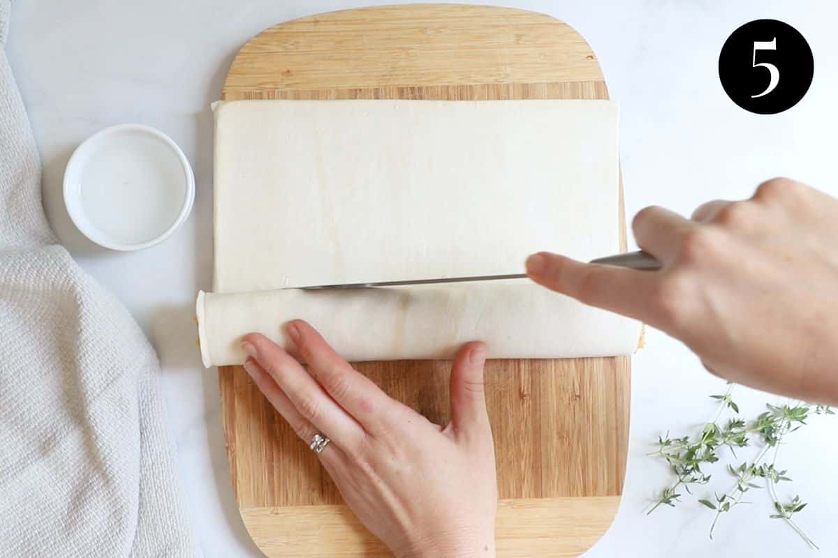 a knife cutting puff pastry to make a sausage roll.