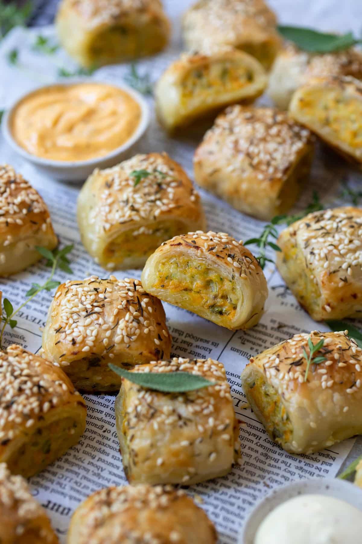 chicken sausage rolls on paper, topped with sage leaves.