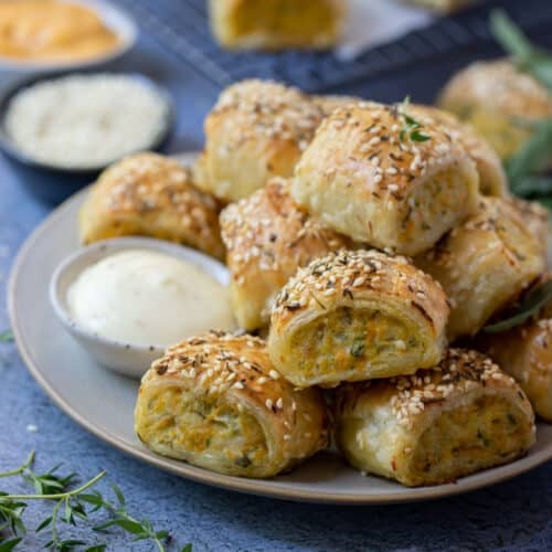 chicken sausage rolls on a plate with dipping sauce.