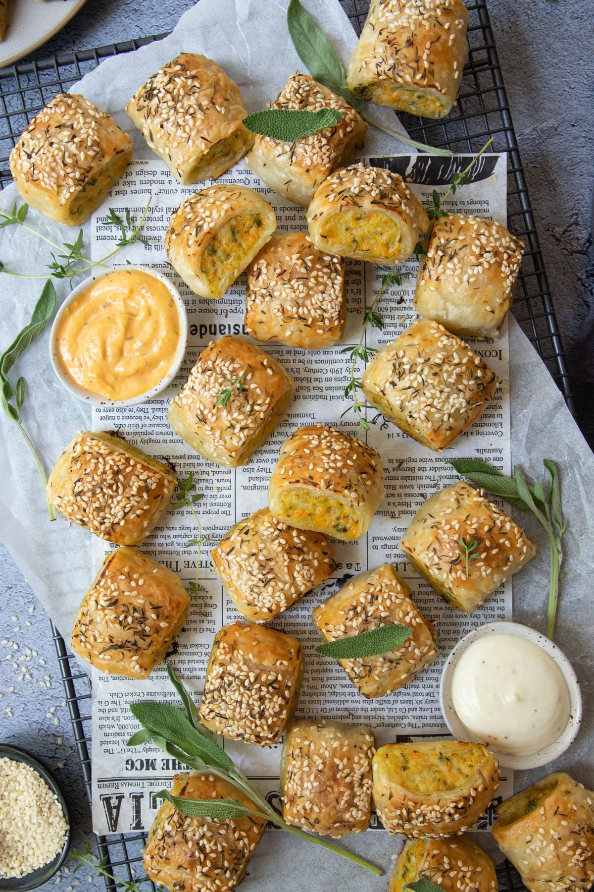 chicken sausage rolls spread over a wire rack, with dipping sauce.