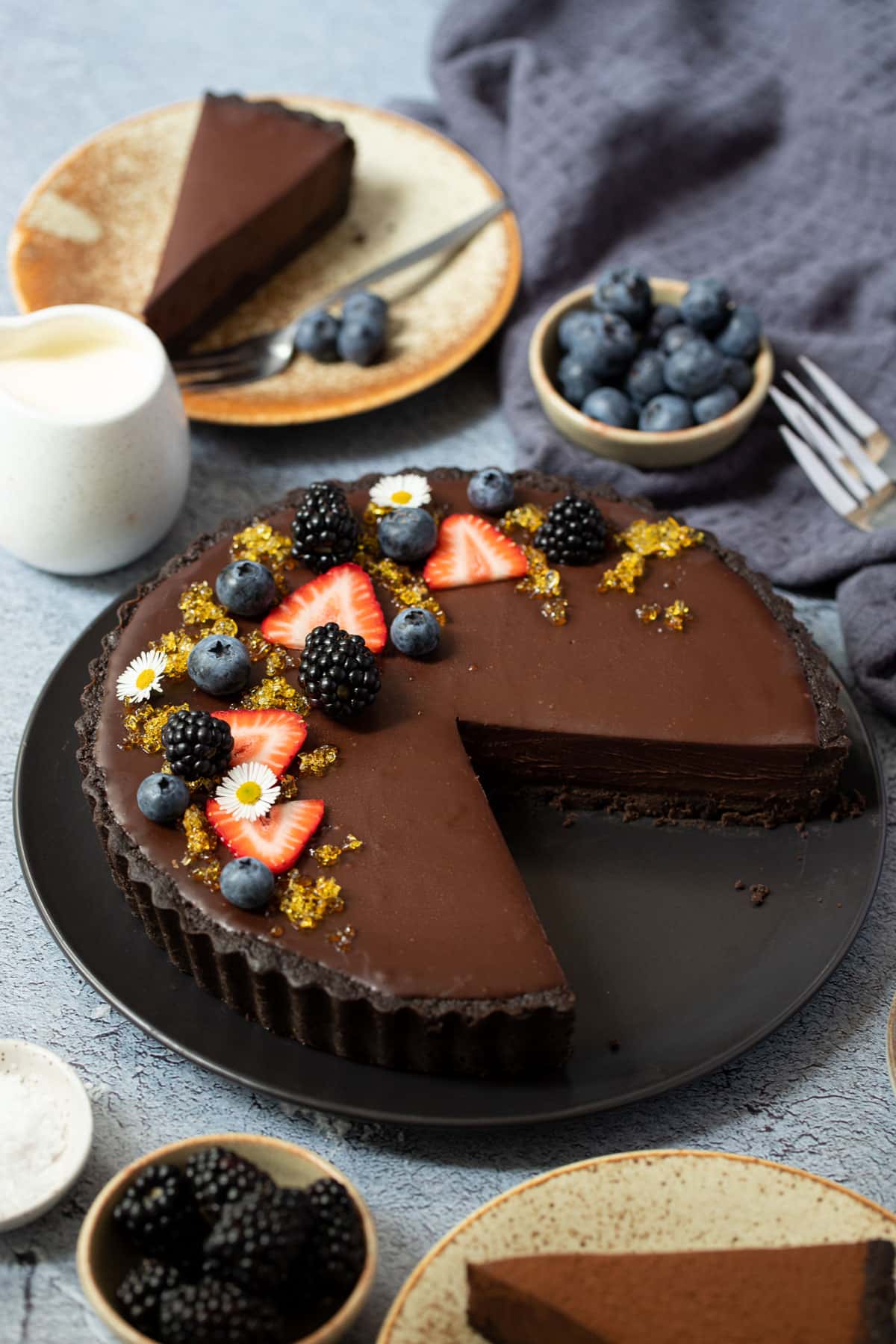 finished chocolate tart on a table, topped with berries.