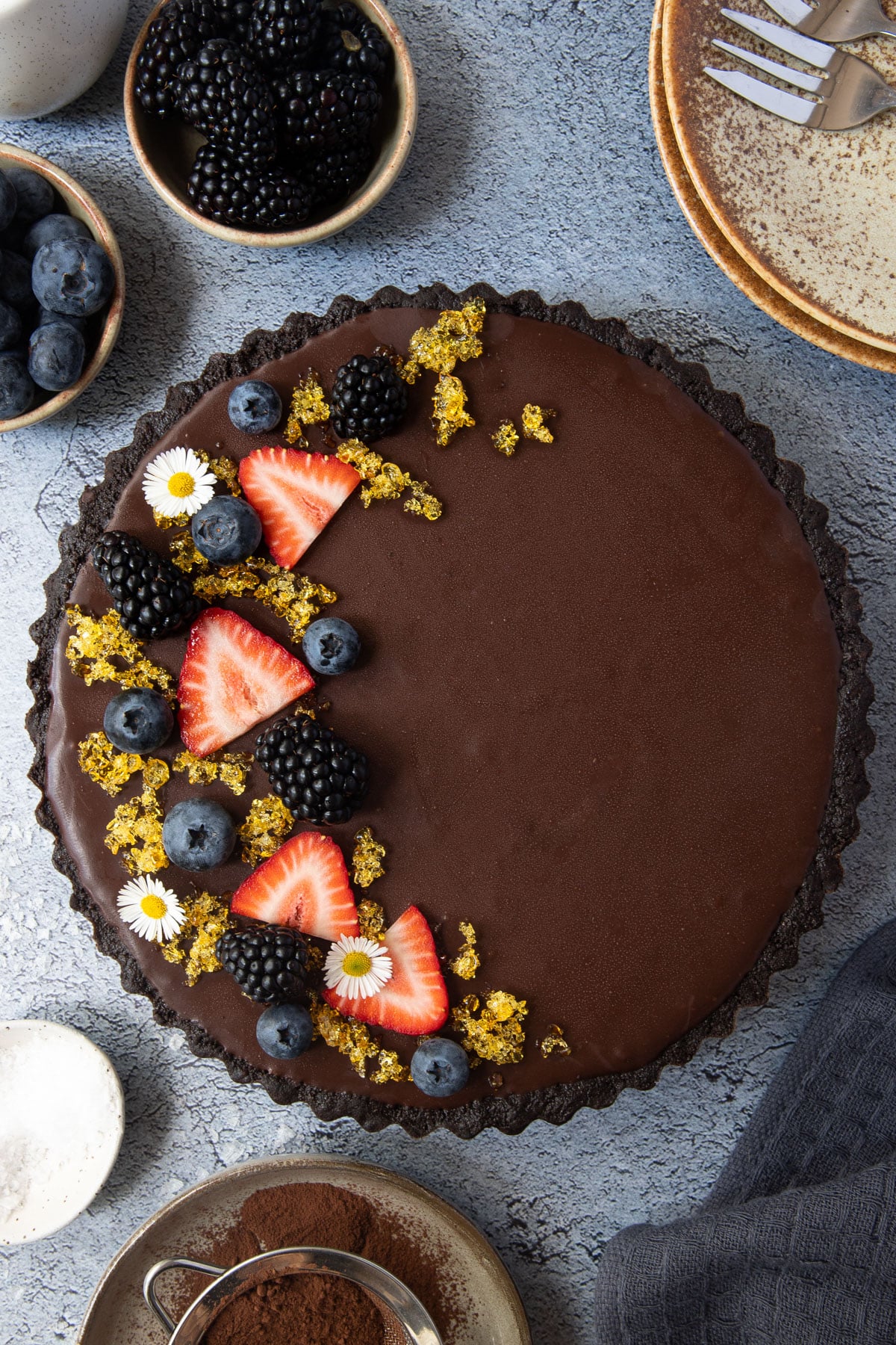 chocolate tart on a table topped with berries and toffee.