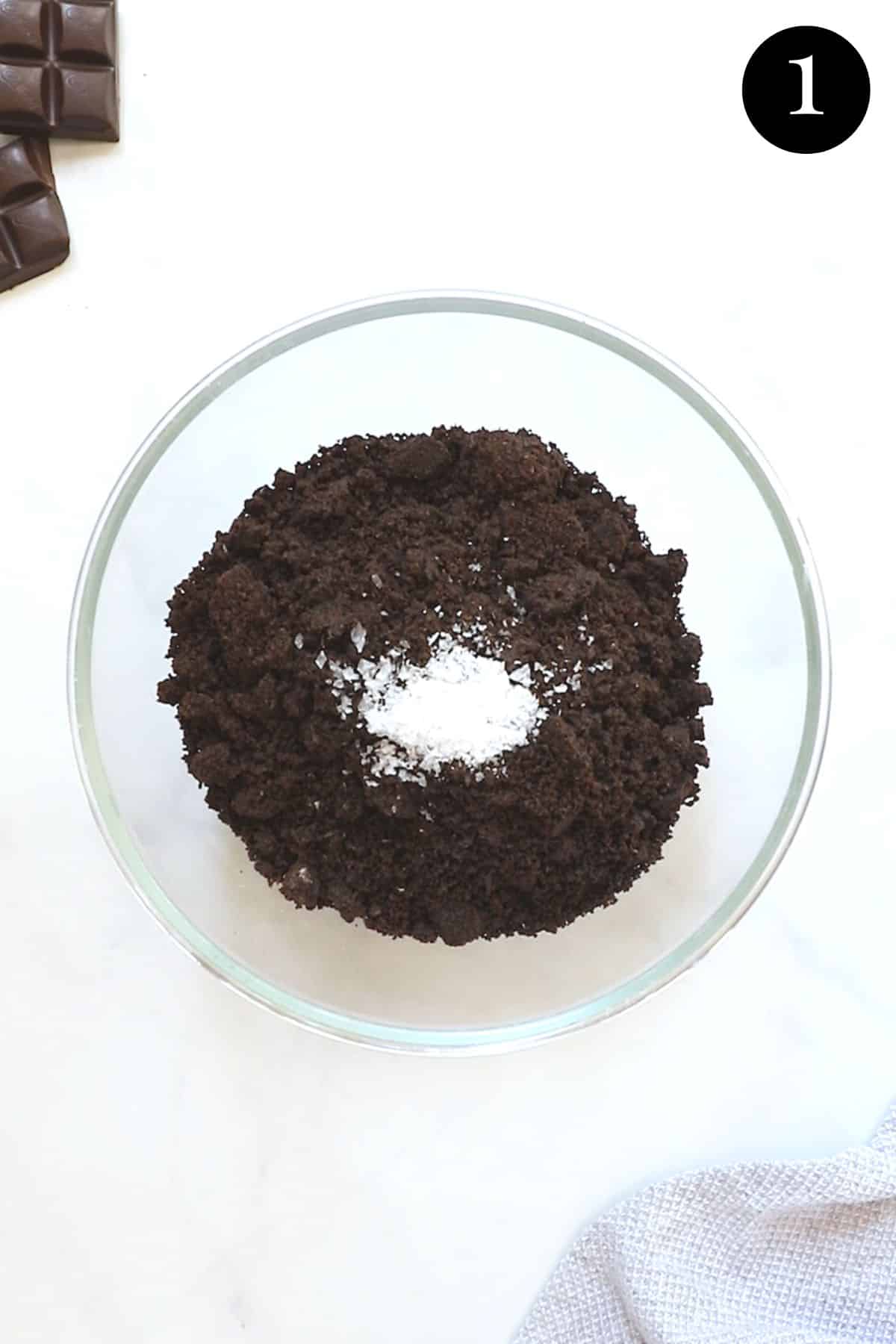 crushed oreos in a bowl with salt and chocolate.