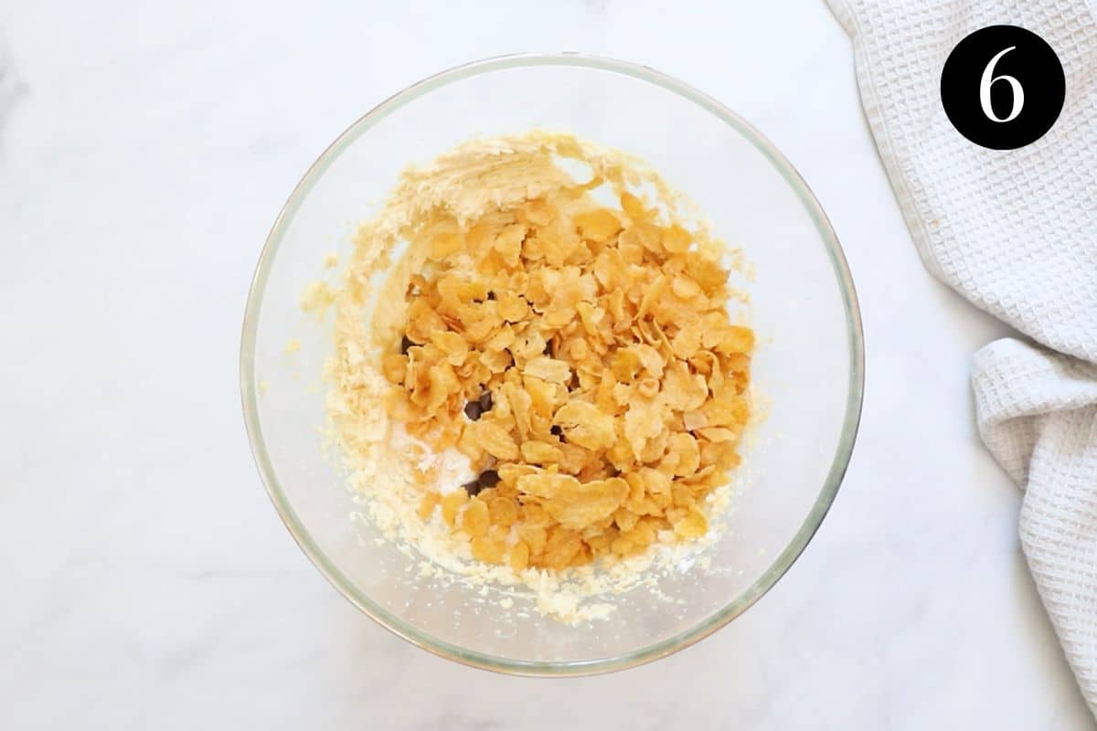 corn flakes and dry ingredients added to butter mixture in a bowl.