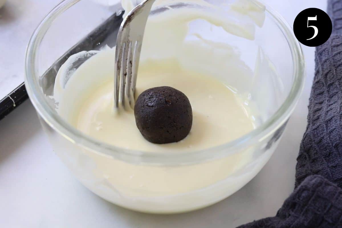 an oreo ball in a bowl of melted chocolate.