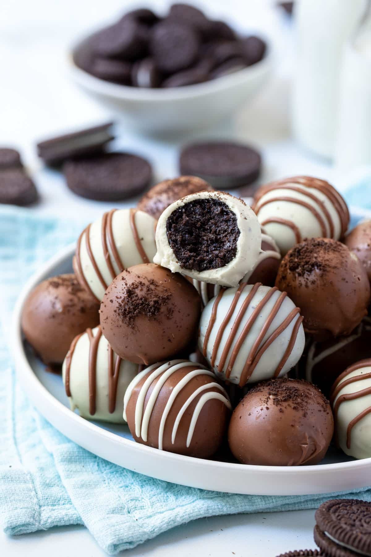 Oreo balls stacked on a plate. The top one has a bite missing.