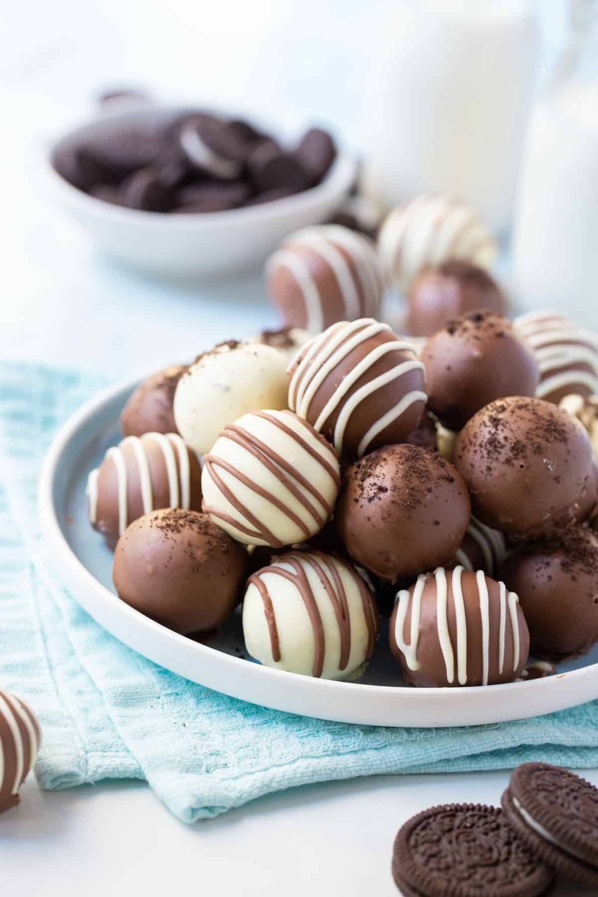 oreo balls on a table with milk and crushed oreos.