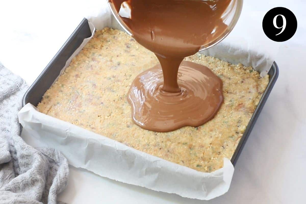 melted chocolate being poured over biscuit base in a tin.