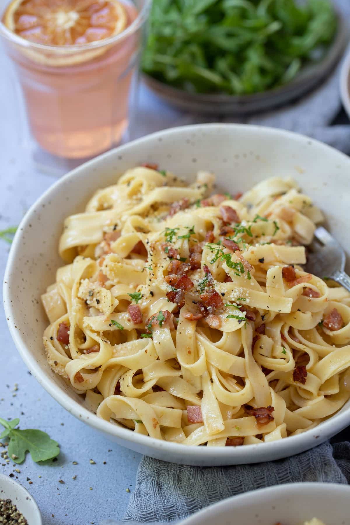 a bowl of fettucine topped with pieces of bacon.