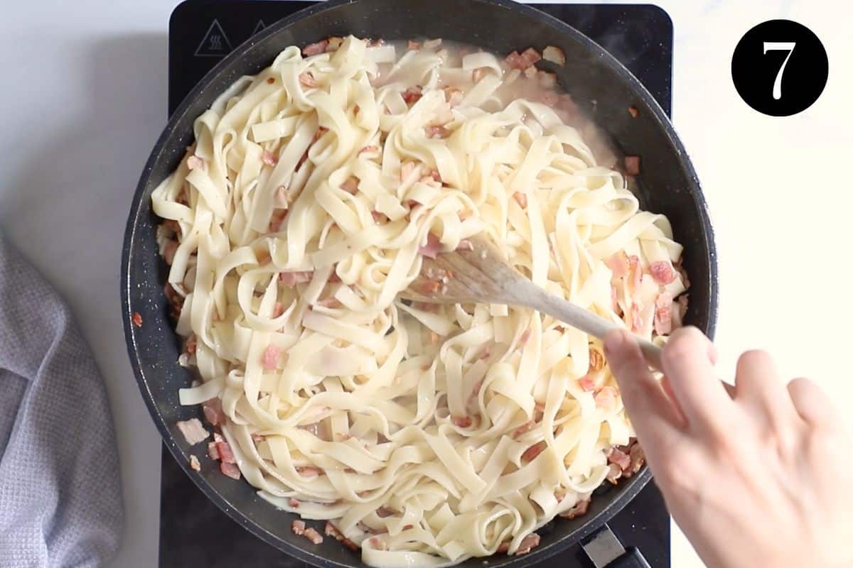 pasta, bacon and pasta water being stirred together in a pan.