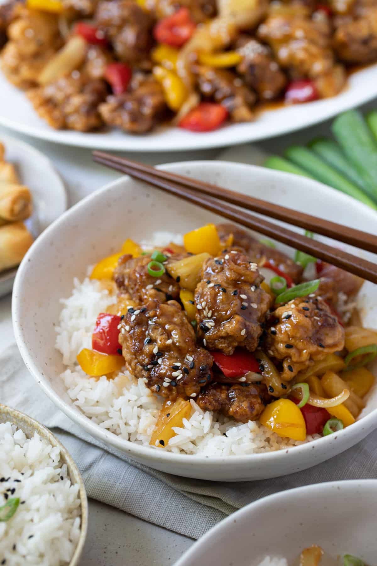 battered sweet and sour pork in a bowl with rice and pieces of pineapple.
