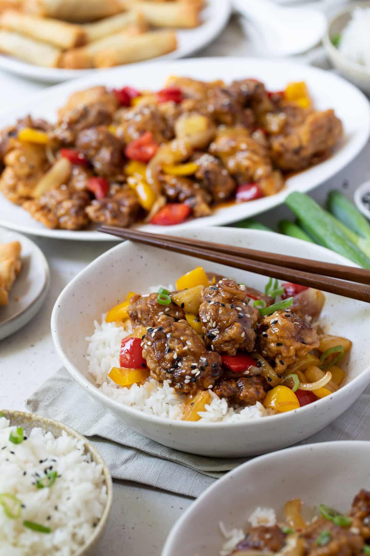 a table with bowls of sweet and sour pork and rice.
