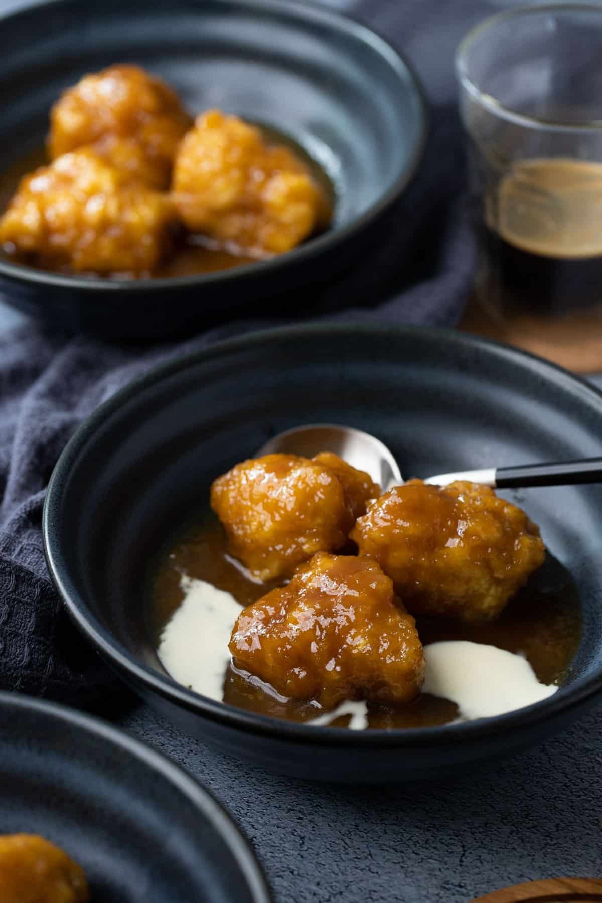 golden syrup dumplings in a bowl topped with cream.