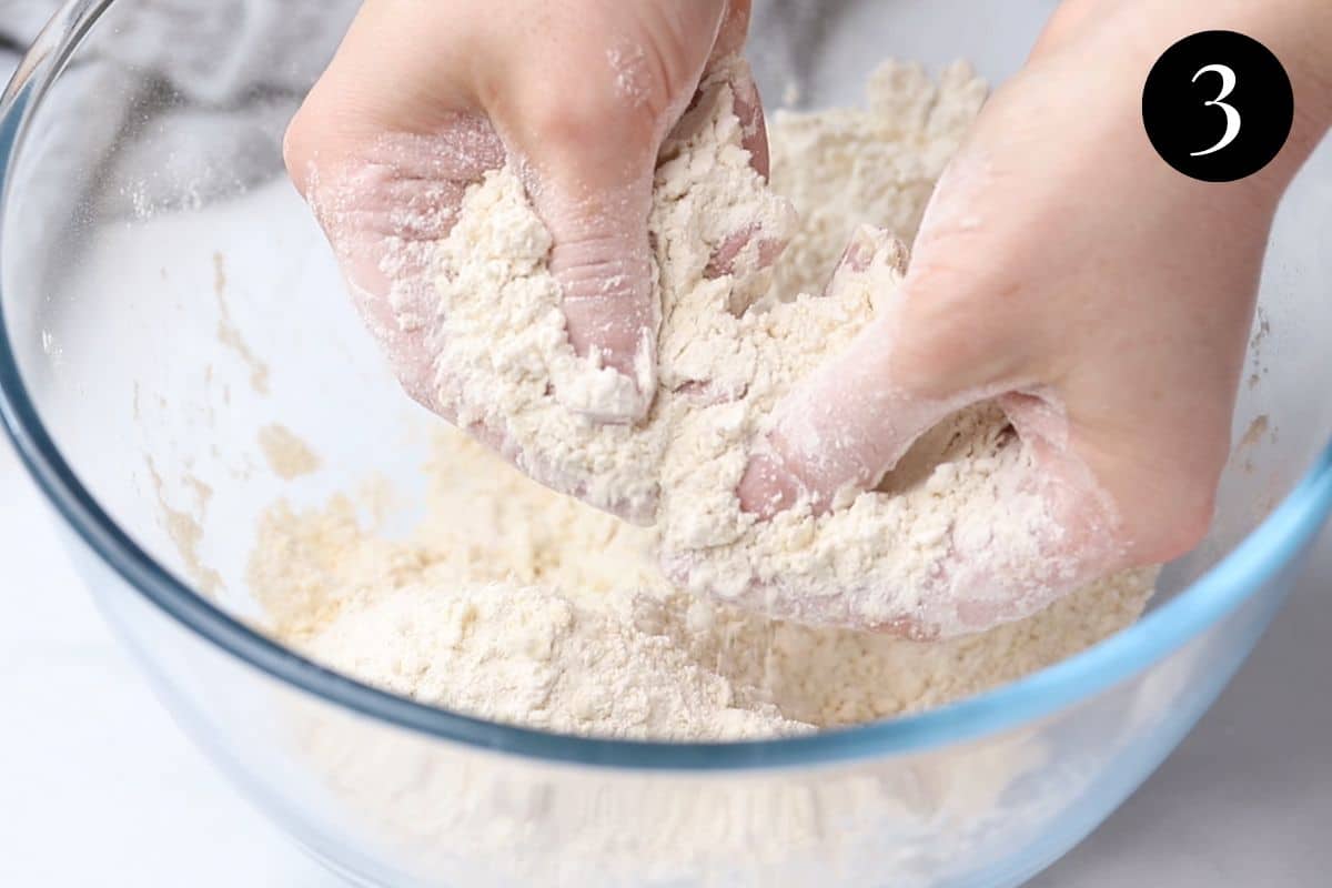 hands rubbing butter into flour in a bowl.