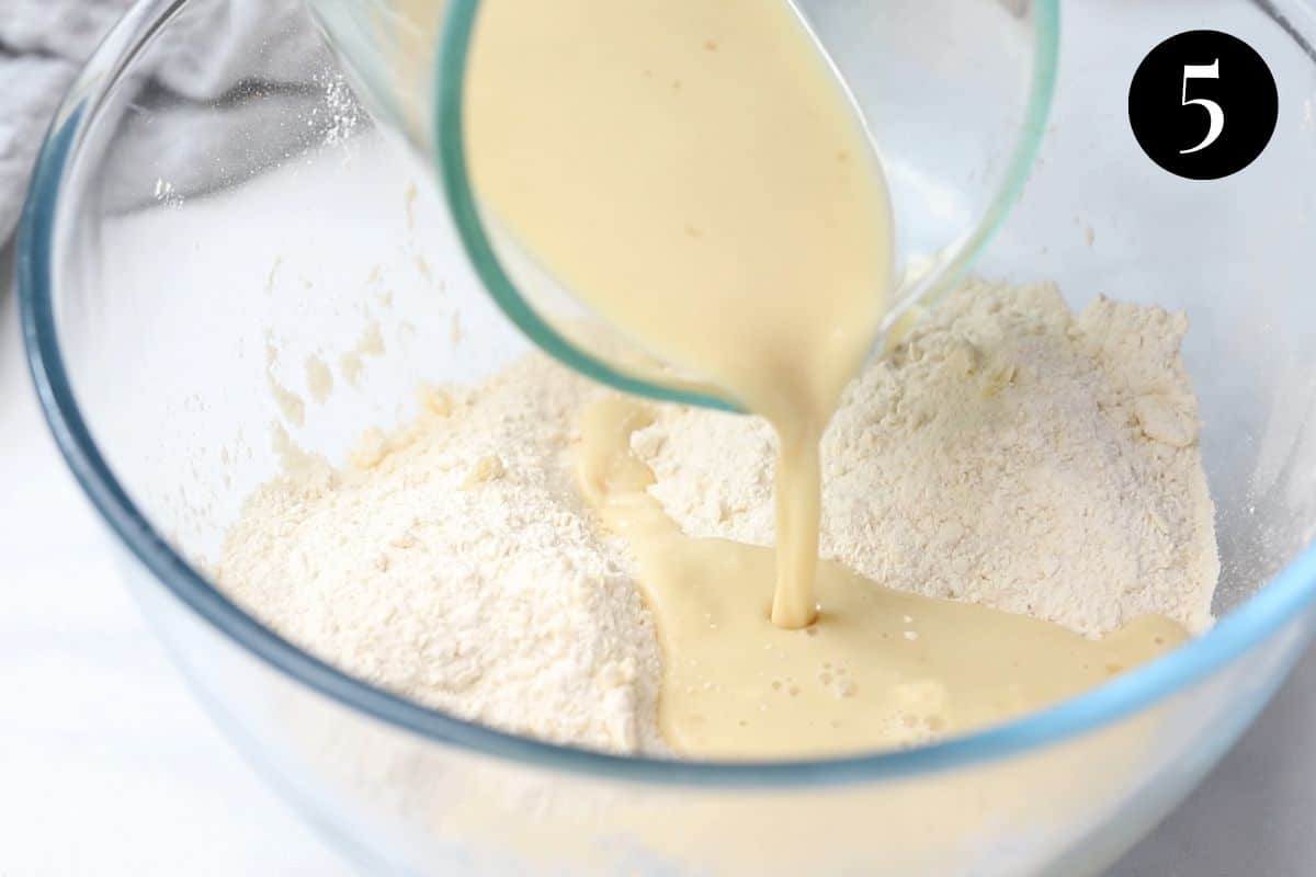 milk mixture being poured into flour in a bowl.