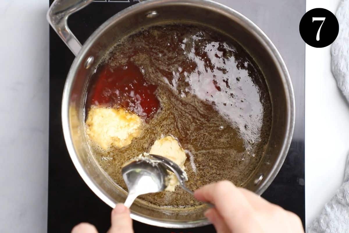 hands adding dumpling mixture to boiling syrup in a pot.