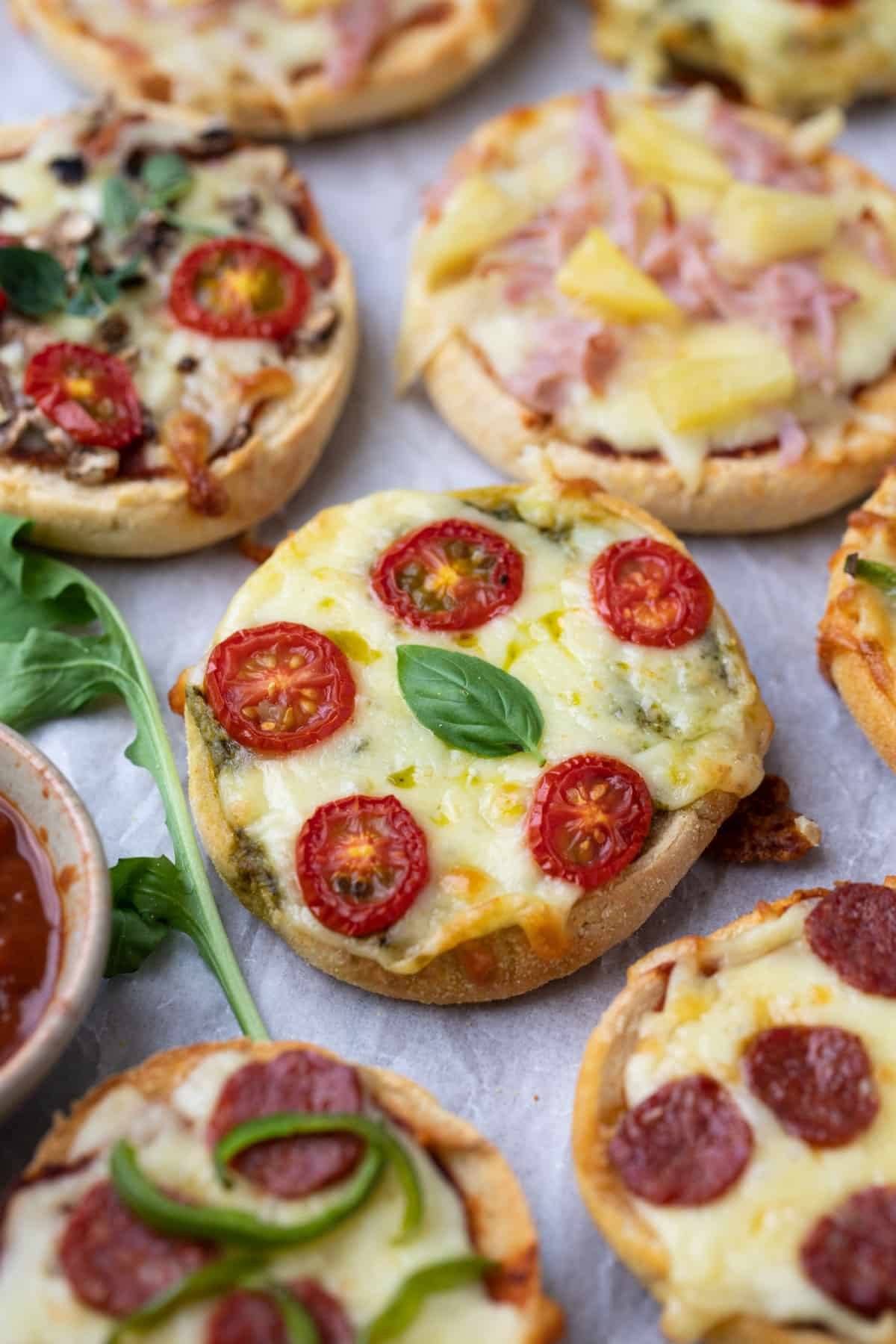 pizza English muffins topped with cheese and tomato on a board.