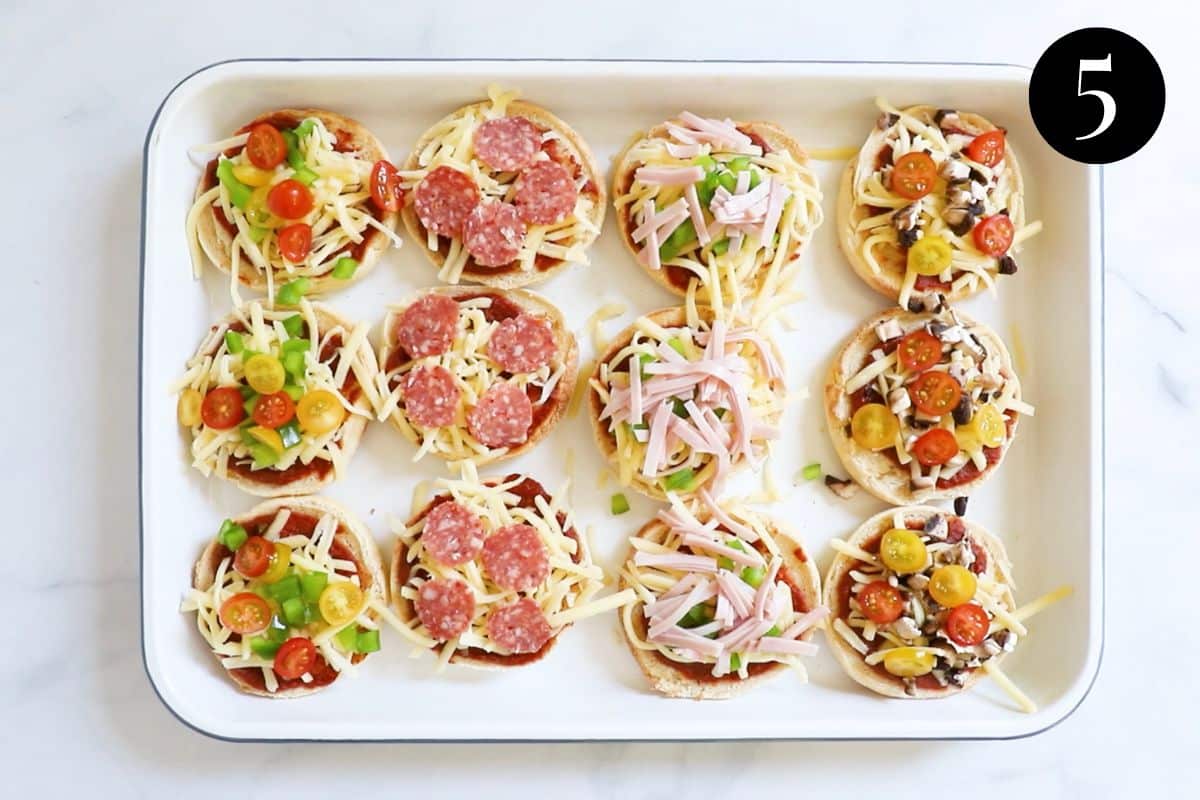 English muffins topped with pizza toppings on a baking tray.