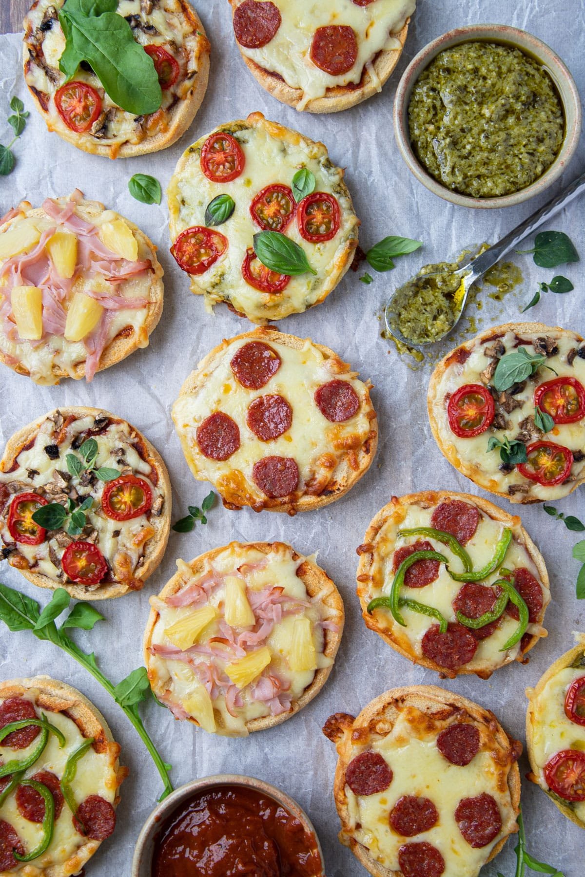 pizza muffins on a tray with pesto and pizza sauce.