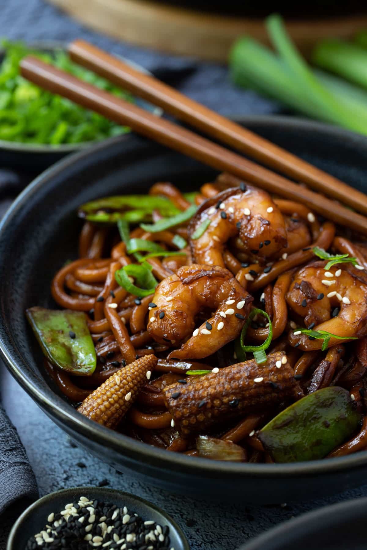 a bowl of noodles, vegetables and prawns, with chopsticks.