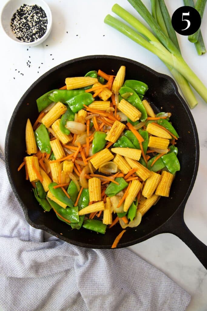 stir fried vegetables in a black pan.