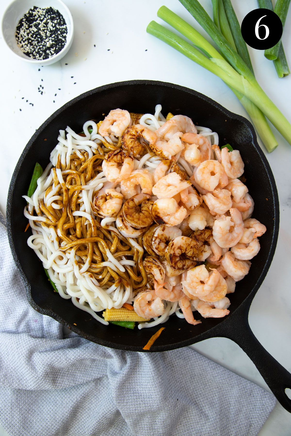 noodles, prawns and stir fried vegetables in a pan with sauce.