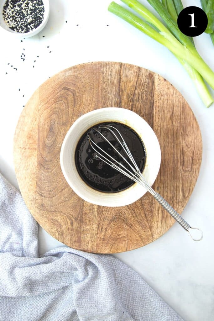 a bowl of stir fry sauce with a whisk.